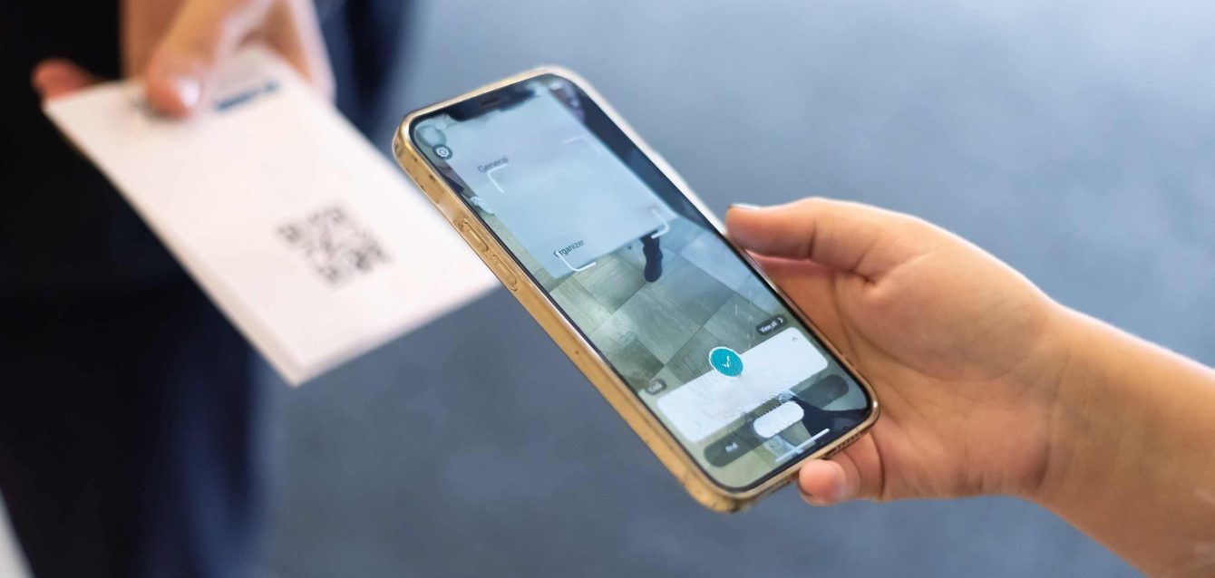 Warehouse manager scanning QR code tracking form on smartphone for instant inventory data sync