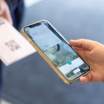 Warehouse manager scanning QR code tracking form on smartphone for instant inventory data sync